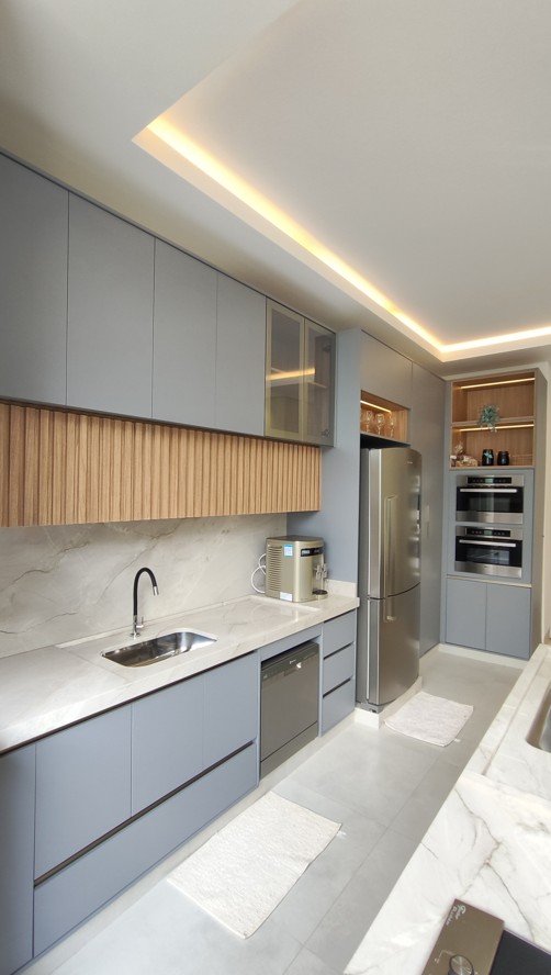 Cozinha planejada da Thonet com armários cinza, painel ripado, bancada e torre de eletrodomésticos