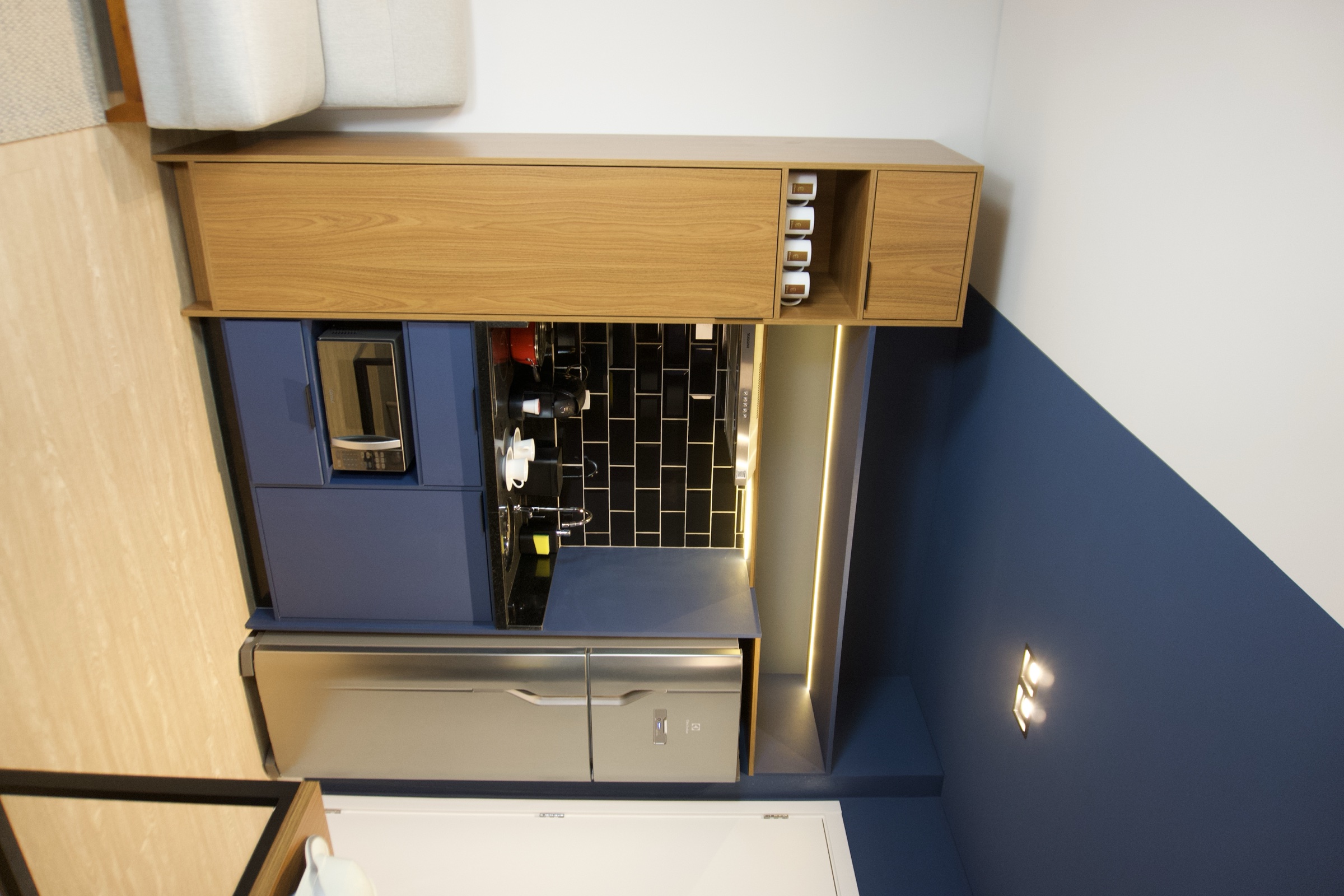 Ambiente gourmet com armários, frigobar e iluminação LED
