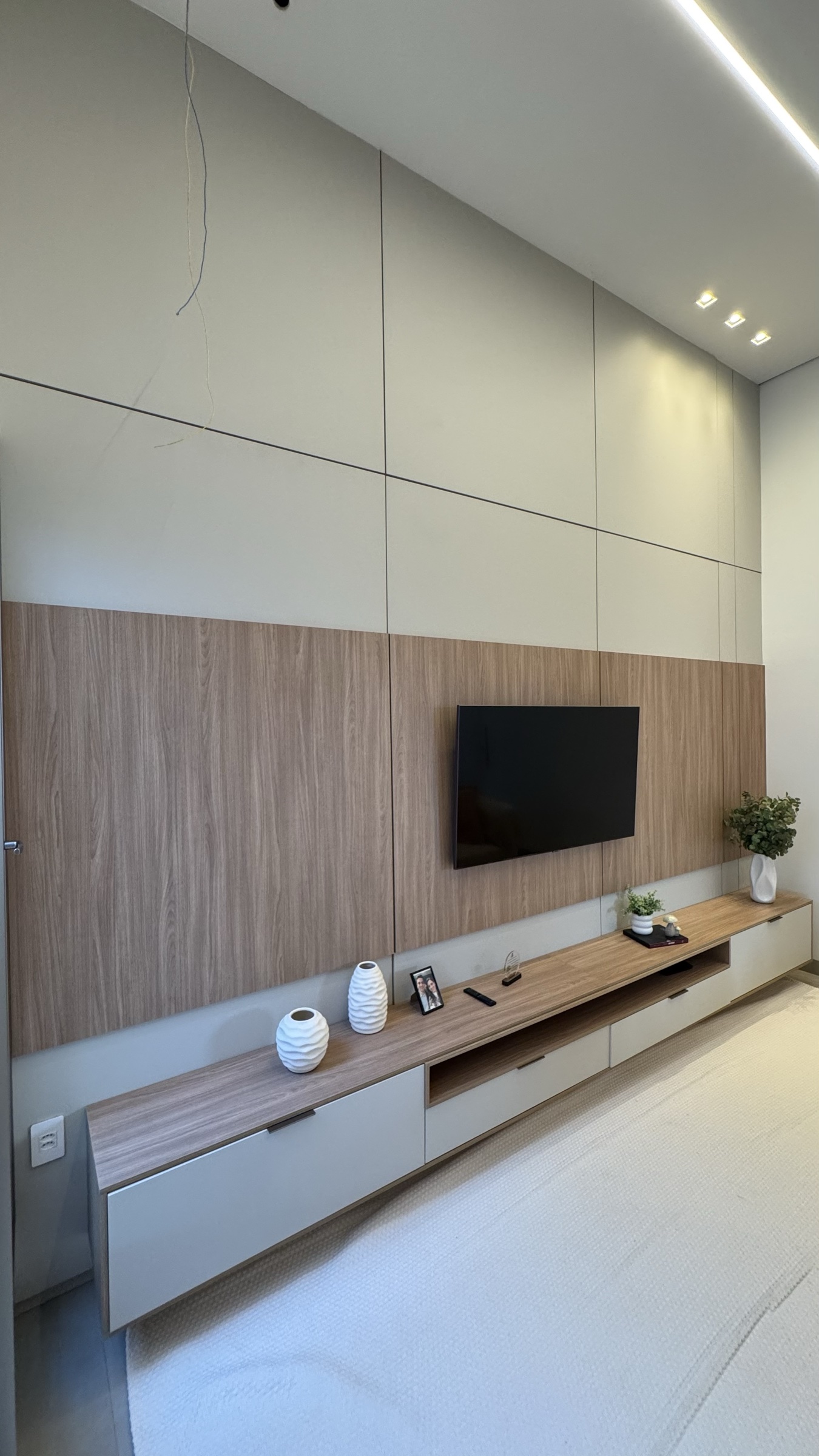 Sala de estar com painel de TV, rack suspenso e iluminação linear